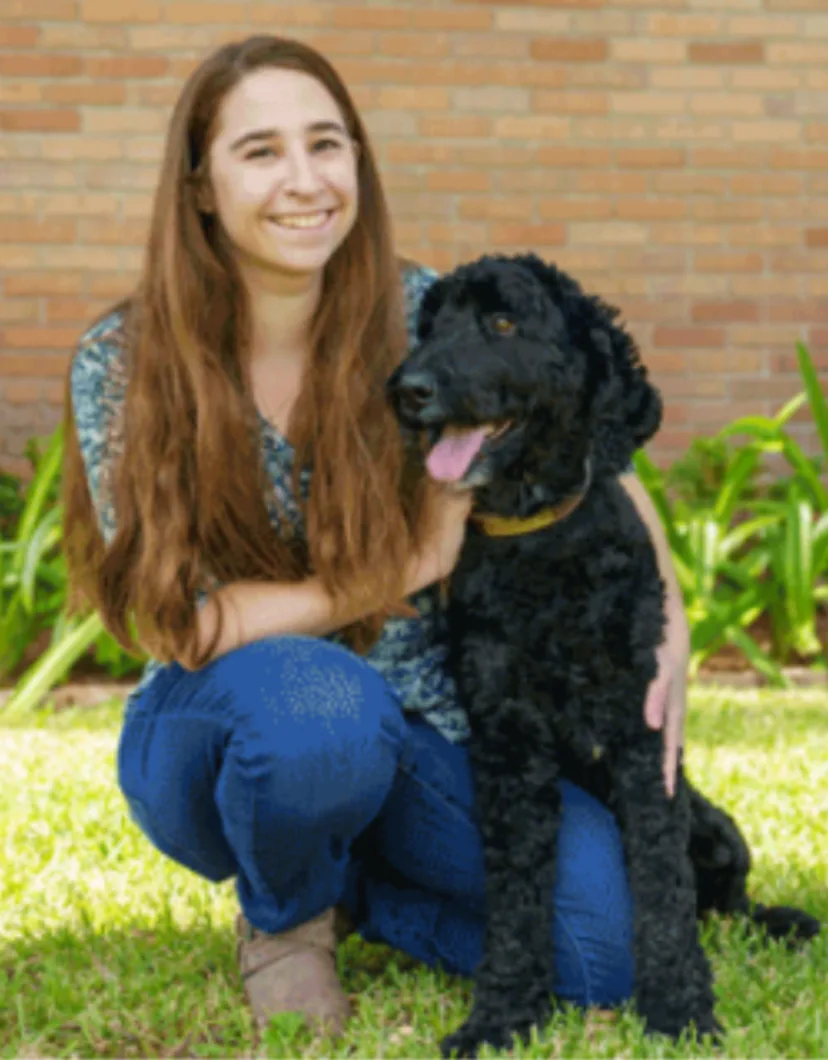 Lauren Hirsch kneeling next to a black dog